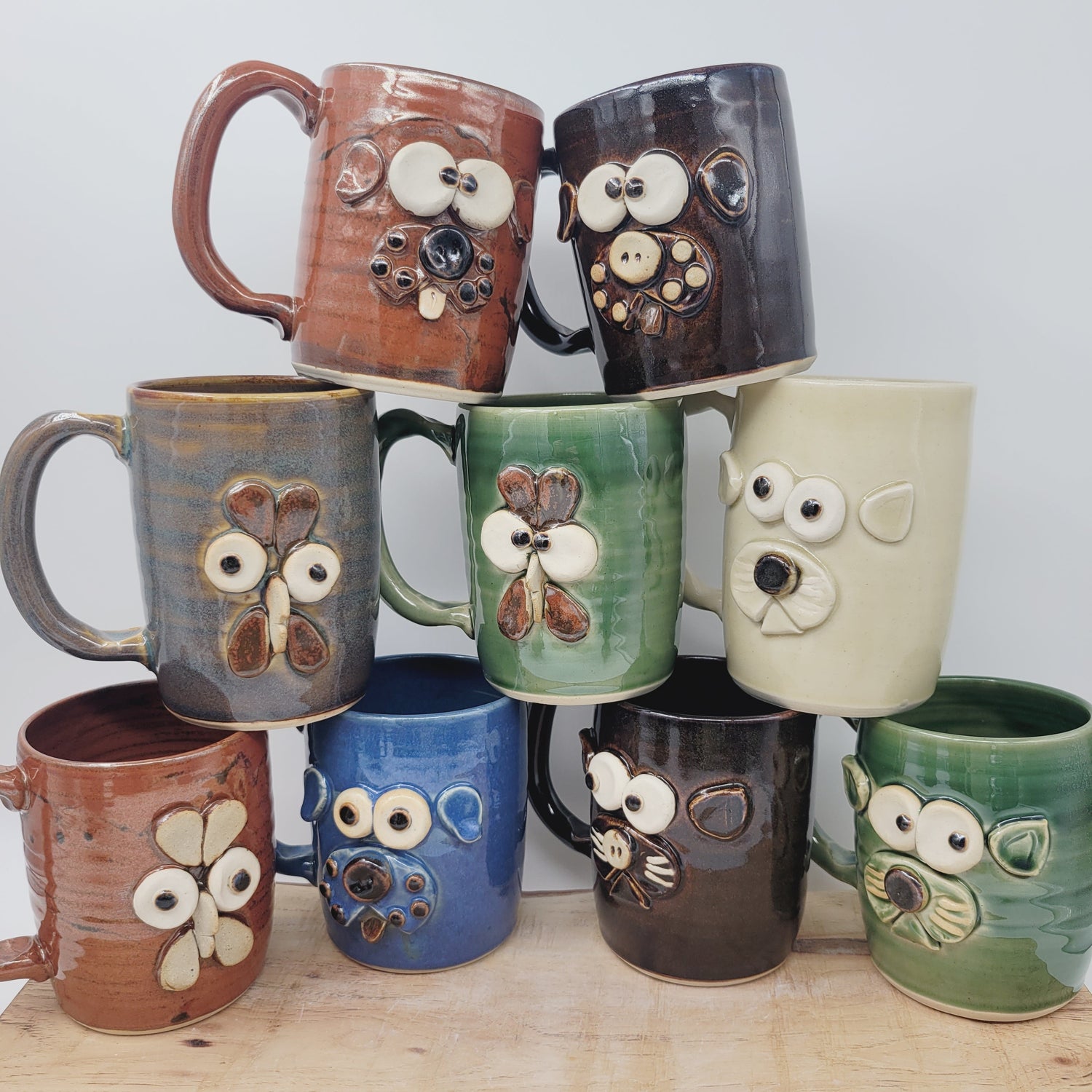 Stack of Pottery mugs featuring different animal faces, such as dogs, cats, and chickens